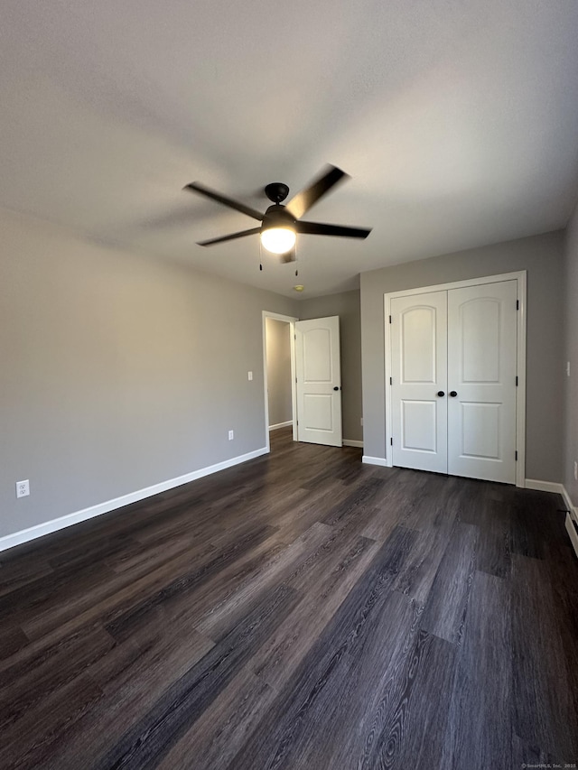 unfurnished bedroom featuring dark wood-style floors, ceiling fan, a closet, and baseboards