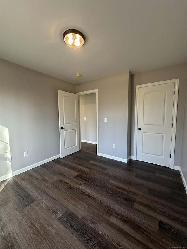 spare room featuring dark wood-style floors and baseboards