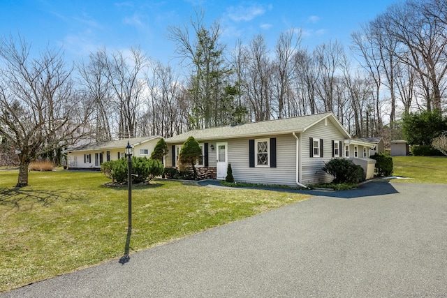 ranch-style house featuring aphalt driveway and a front lawn
