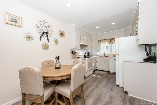 kitchen with under cabinet range hood, light countertops, recessed lighting, dark wood-style floors, and white appliances