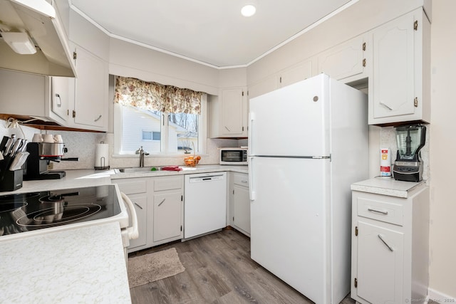 kitchen with white appliances, wood finished floors, decorative backsplash, under cabinet range hood, and crown molding