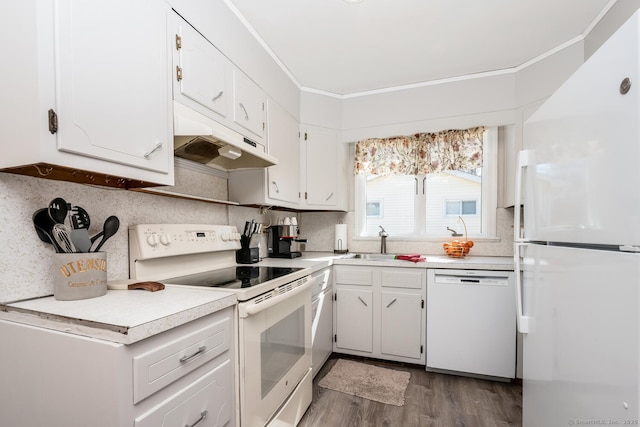 kitchen featuring dark wood-type flooring, ornamental molding, under cabinet range hood, a sink, and white appliances