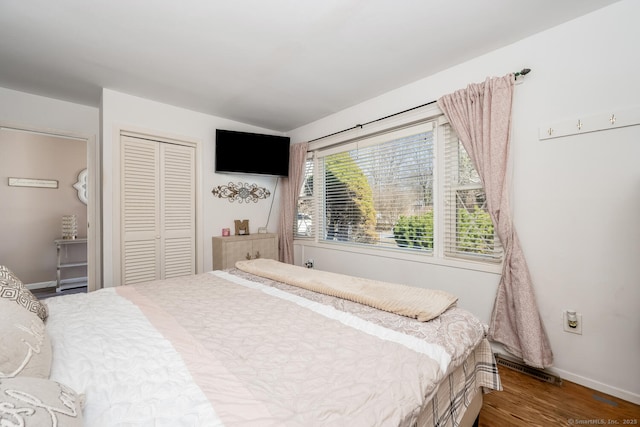 bedroom with a closet, baseboards, visible vents, and wood finished floors