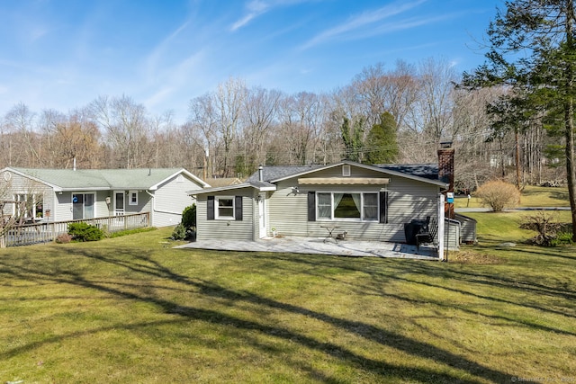 back of property featuring a yard, a patio, and a chimney