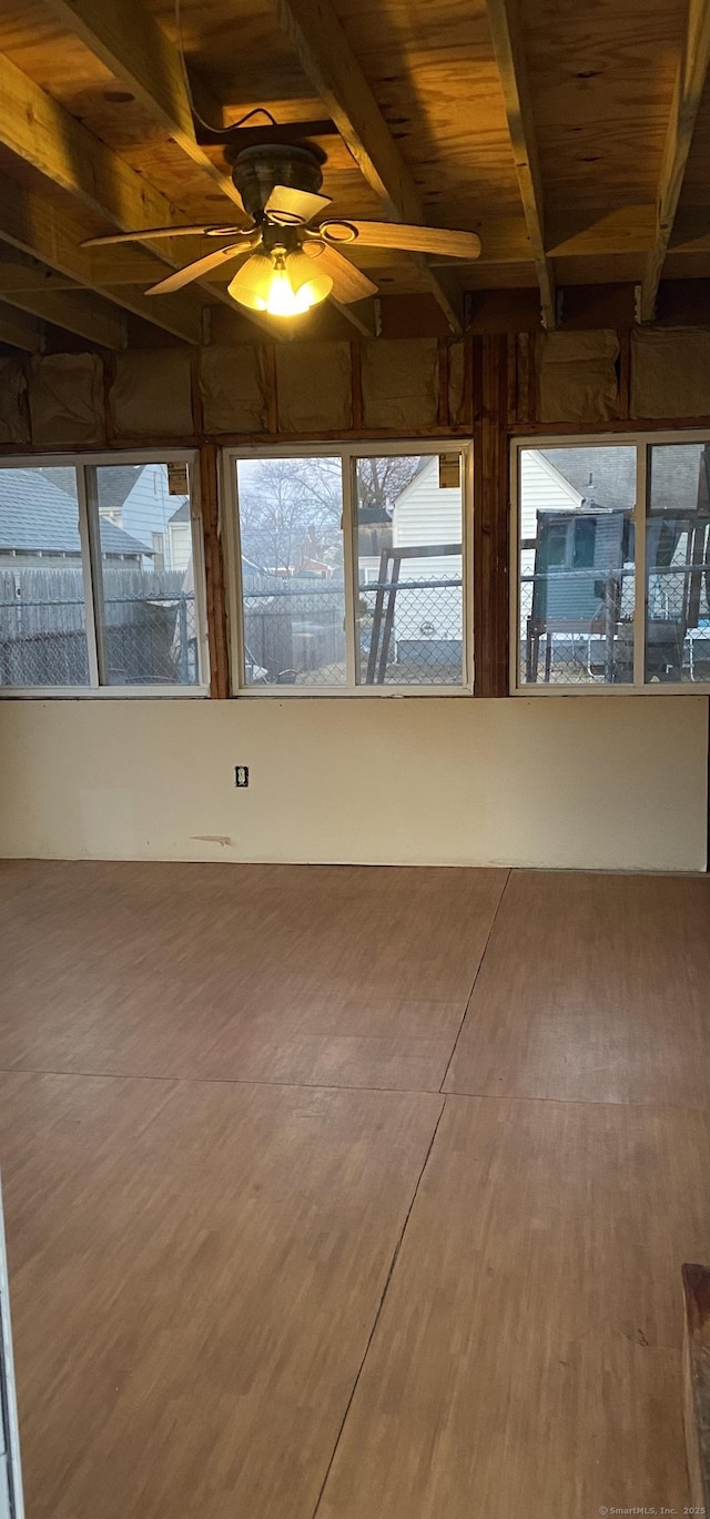 unfurnished sunroom featuring beamed ceiling and ceiling fan