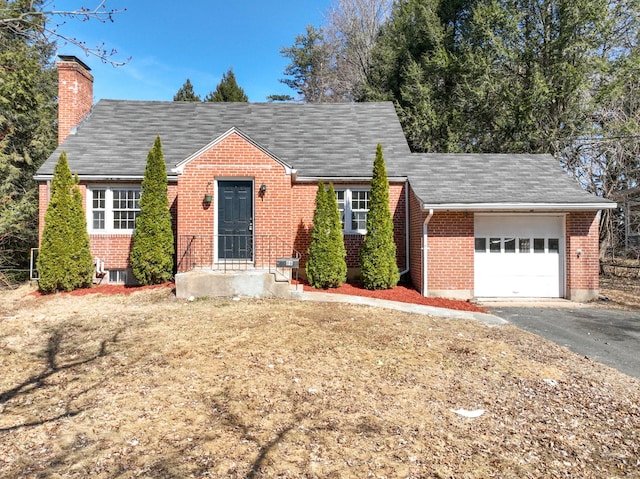 view of front facade with an attached garage, brick siding, driveway, and a chimney