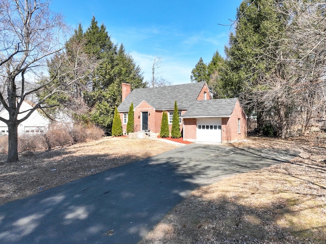 view of front of house with roof with shingles, driveway, an attached garage, a chimney, and brick siding