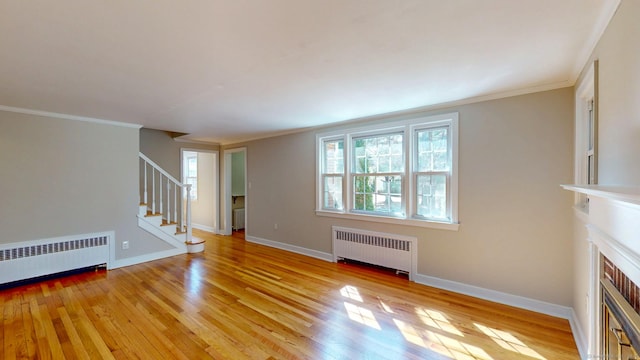 unfurnished living room with stairway, baseboards, radiator heating unit, and light wood-style floors