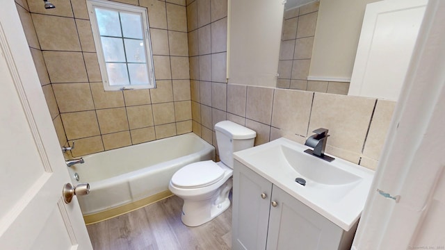 full bathroom featuring toilet, wood finished floors, tile walls, decorative backsplash, and vanity