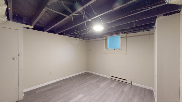 below grade area featuring a baseboard heating unit, baseboards, and wood finished floors