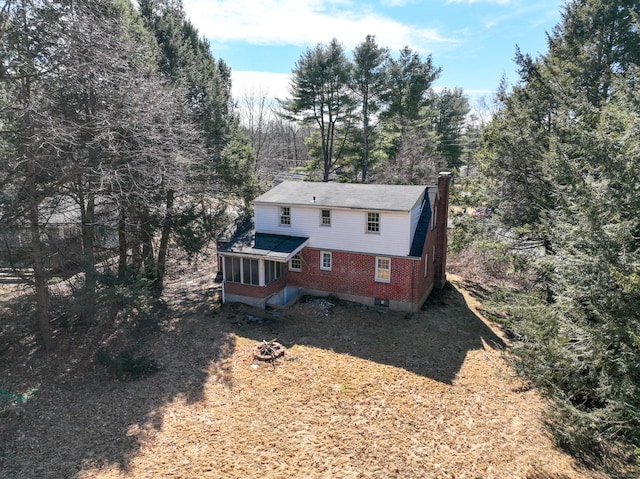 back of house with a chimney and a sunroom