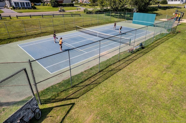 view of tennis court with a yard and fence