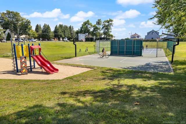 community play area featuring a tennis court, a lawn, fence, and community basketball court