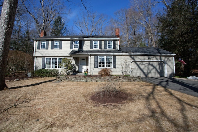 view of front of house with aphalt driveway, an attached garage, and a chimney