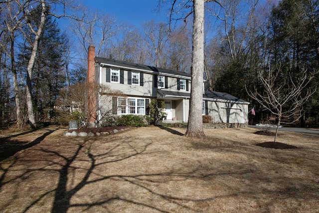 colonial house featuring a garage and a chimney