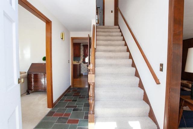 staircase featuring baseboards and stone finish flooring