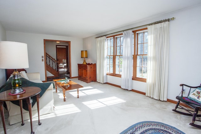 living area featuring stairway, baseboards, and carpet