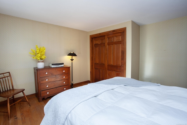 bedroom featuring wallpapered walls, light wood-style floors, a closet, and baseboards