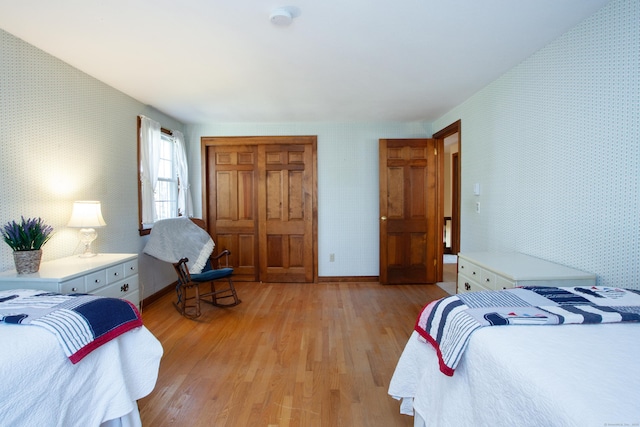 bedroom featuring light wood-style flooring, wallpapered walls, and baseboards