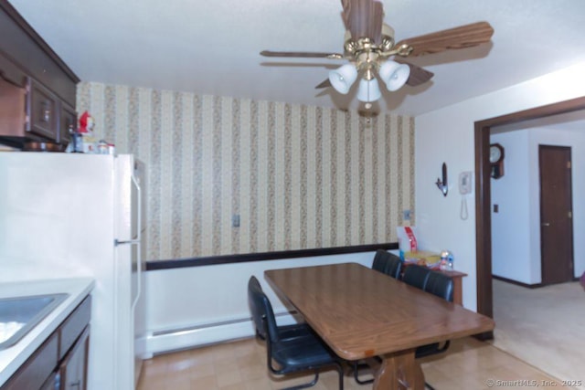 dining space with a baseboard radiator, light floors, and ceiling fan