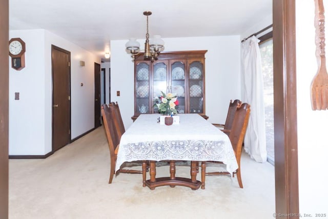 dining room featuring baseboards, light colored carpet, and an inviting chandelier