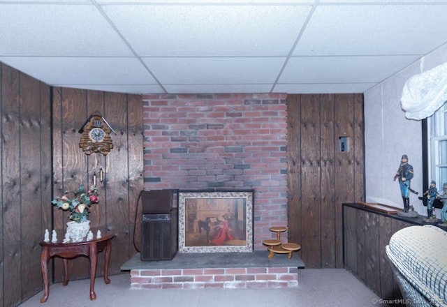 carpeted living area featuring a paneled ceiling and wood walls