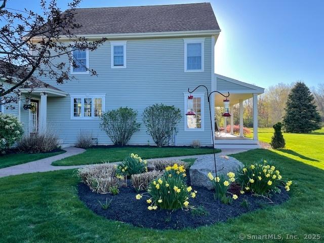 view of side of home with a lawn and roof with shingles