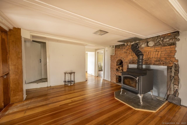 unfurnished living room featuring wood finished floors and a wood stove