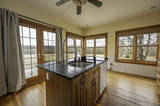 kitchen with light wood-style flooring, wainscoting, ceiling fan, and a sink