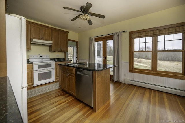 kitchen featuring a sink, hardwood / wood-style flooring, white appliances, a wainscoted wall, and under cabinet range hood