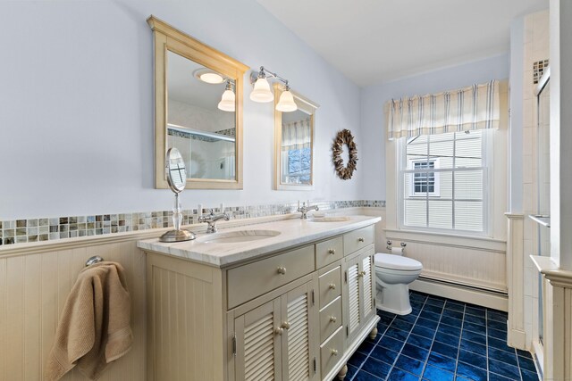 bathroom with a sink, a baseboard radiator, toilet, and a wainscoted wall