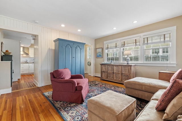 living area with recessed lighting, a baseboard heating unit, and hardwood / wood-style flooring