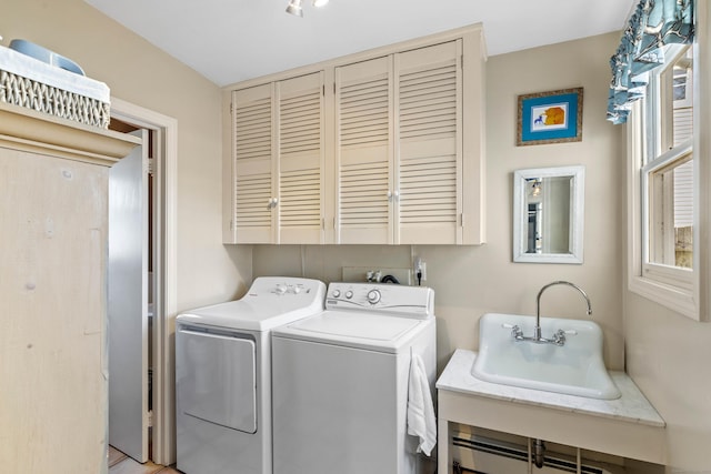 washroom with cabinet space, washer and dryer, and a sink