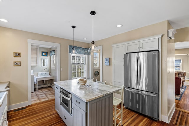 kitchen featuring a breakfast bar, dark wood-style floors, recessed lighting, stainless steel appliances, and hanging light fixtures