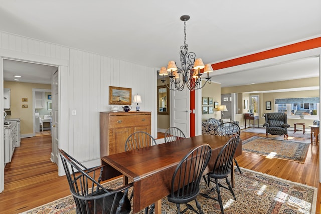 dining space with baseboards, an inviting chandelier, and light wood finished floors