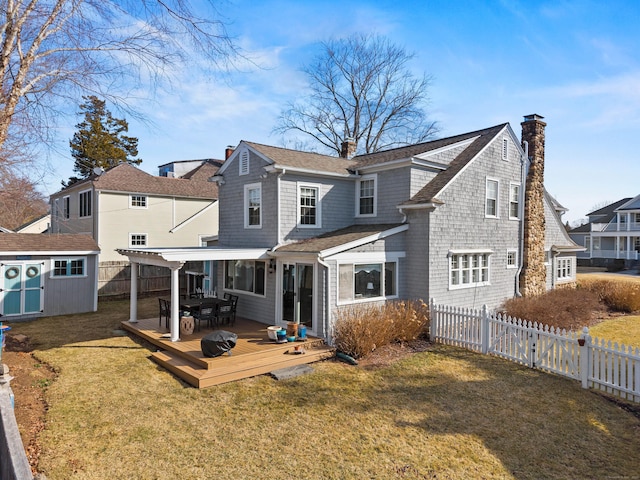 rear view of house featuring a chimney, a yard, a fenced backyard, an outbuilding, and a storage unit