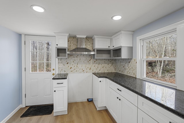 129 Smith Rd, East Haddam, CT 06423 - kitchen featuring wall chimney range hood, light wood finished floors, dark stone counters, and decorative backsplash
