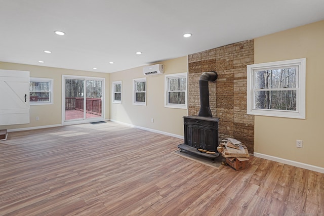 129 Smith Rd, East Haddam, CT 06423 - unfurnished living room featuring wood finished floors, a wood stove, an AC wall unit, and baseboards