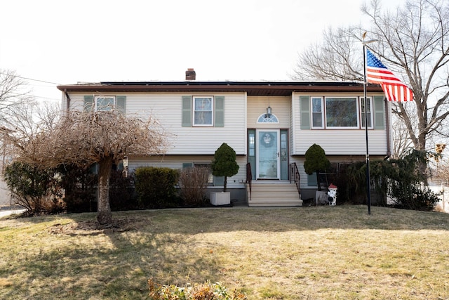 bi-level home with a chimney, a front lawn, and entry steps