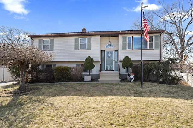 bi-level home with entry steps, a chimney, and a front yard