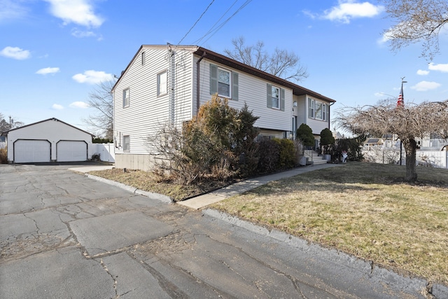 view of front of house featuring a detached garage, an outbuilding, and a front yard