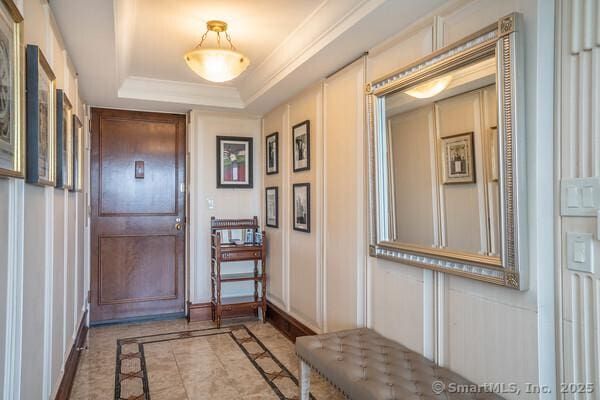 interior space with baseboards, a raised ceiling, and crown molding