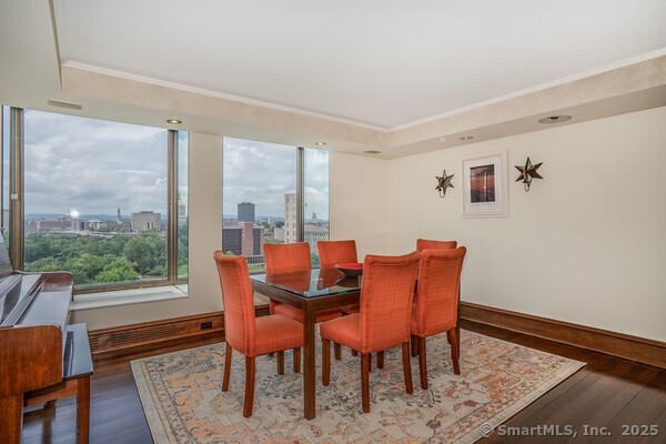 dining space with a view of city, baseboards, and wood finished floors