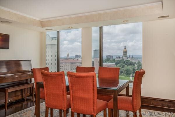 dining room featuring crown molding, a view of city, wood finished floors, and visible vents