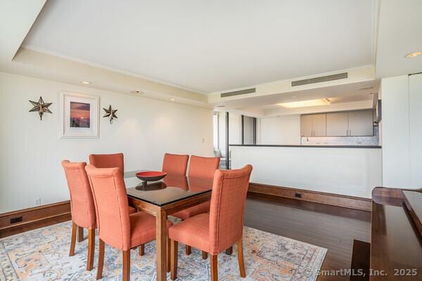 dining area featuring visible vents, a raised ceiling, light wood-type flooring, and baseboards