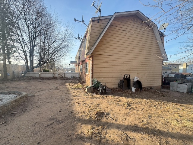 view of property exterior featuring a gambrel roof and fence