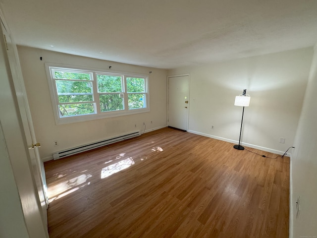 unfurnished room with wood finished floors, baseboards, and a baseboard radiator