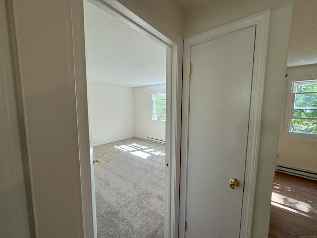 hallway featuring baseboards, carpet floors, and baseboard heating