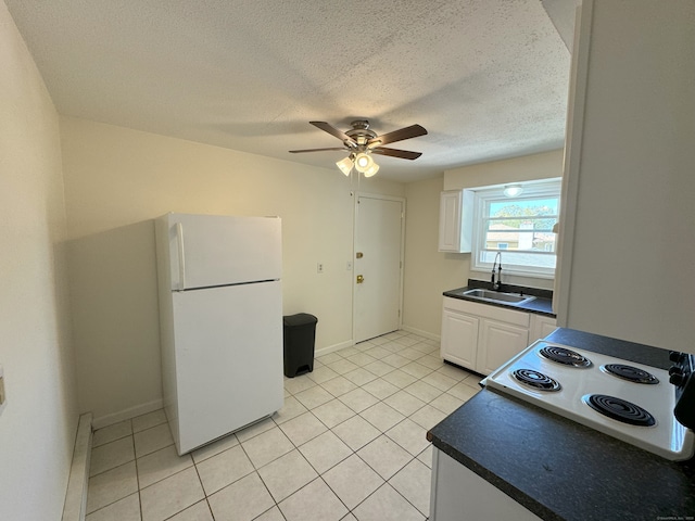 kitchen with dark countertops, stovetop, white cabinets, and a sink