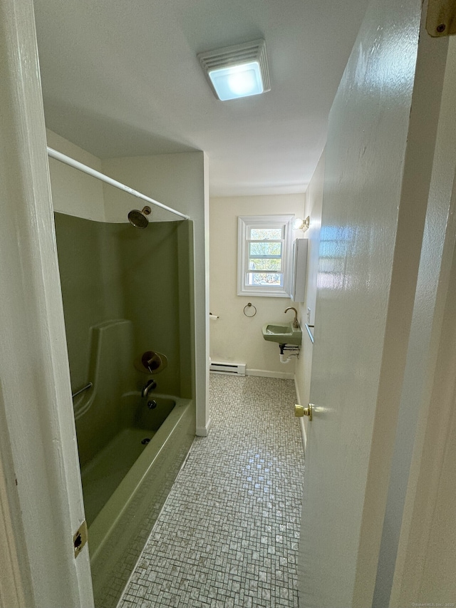 bathroom with washtub / shower combination, baseboards, baseboard heating, and a sink